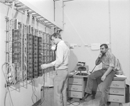 882193 Afbeelding van twee monteurs aan het werk in de telefooncentrale van het Stadhuis (Stadhuisbrug 1) te Utrecht.